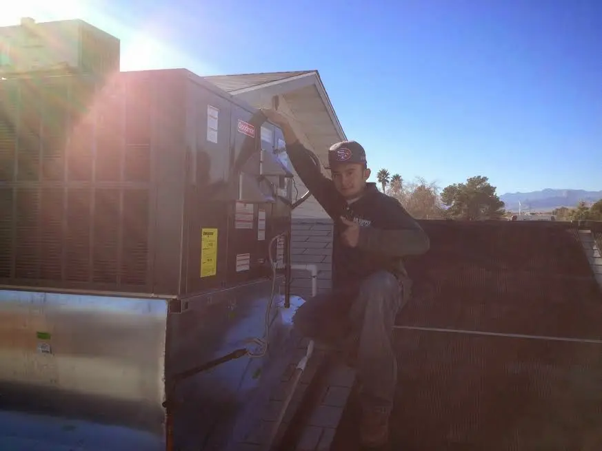 HVAC technician performing AC Tune-Up on a rooftop unit in Three Lakes